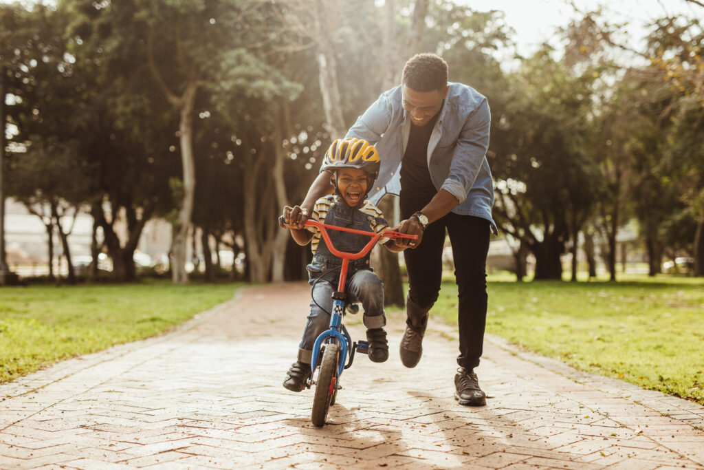 A man helping a child ride a bike