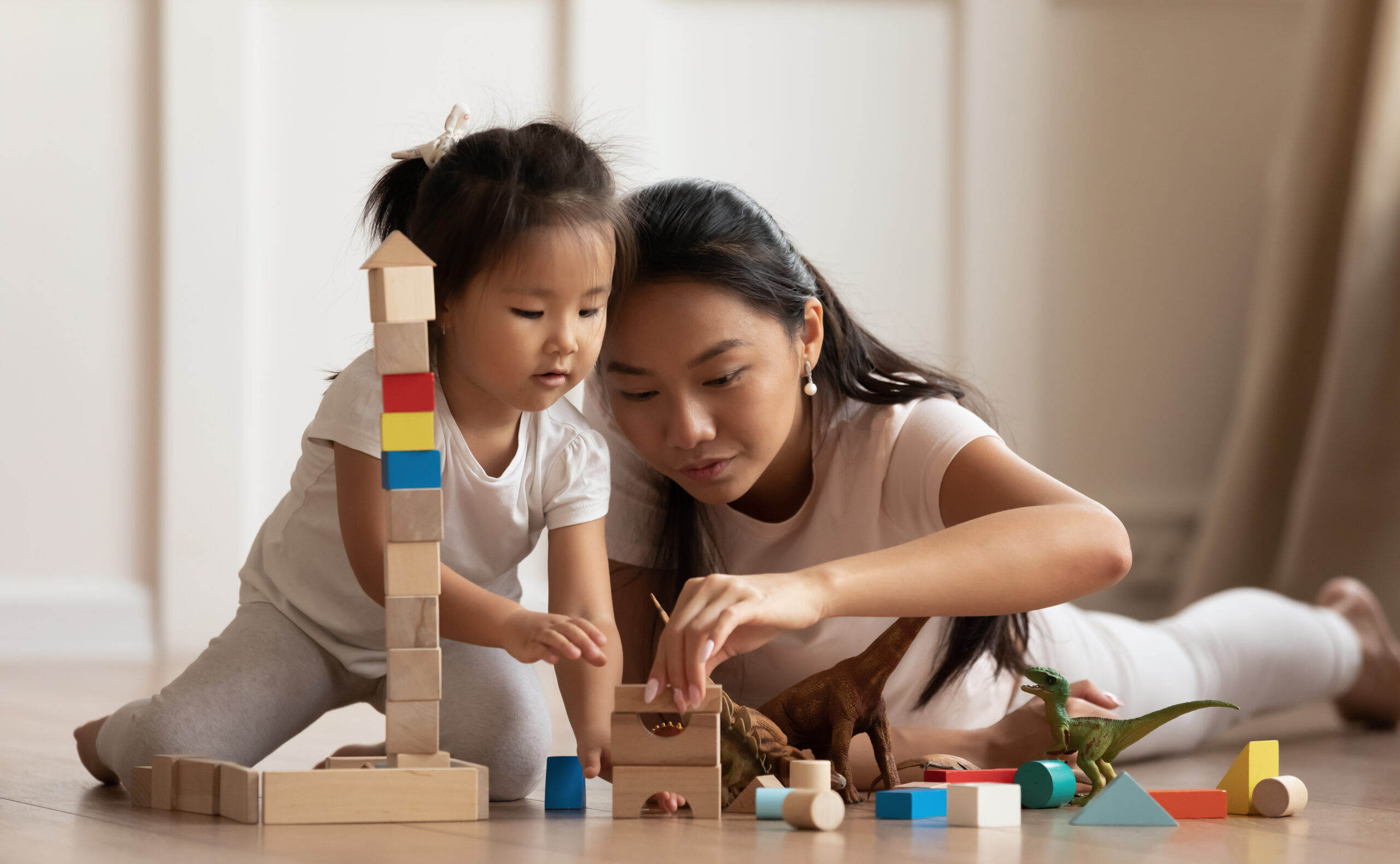 A woman and child playing with blocks on the floor.