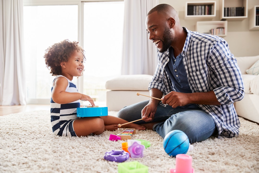 A man and child playing with toys on the floor.