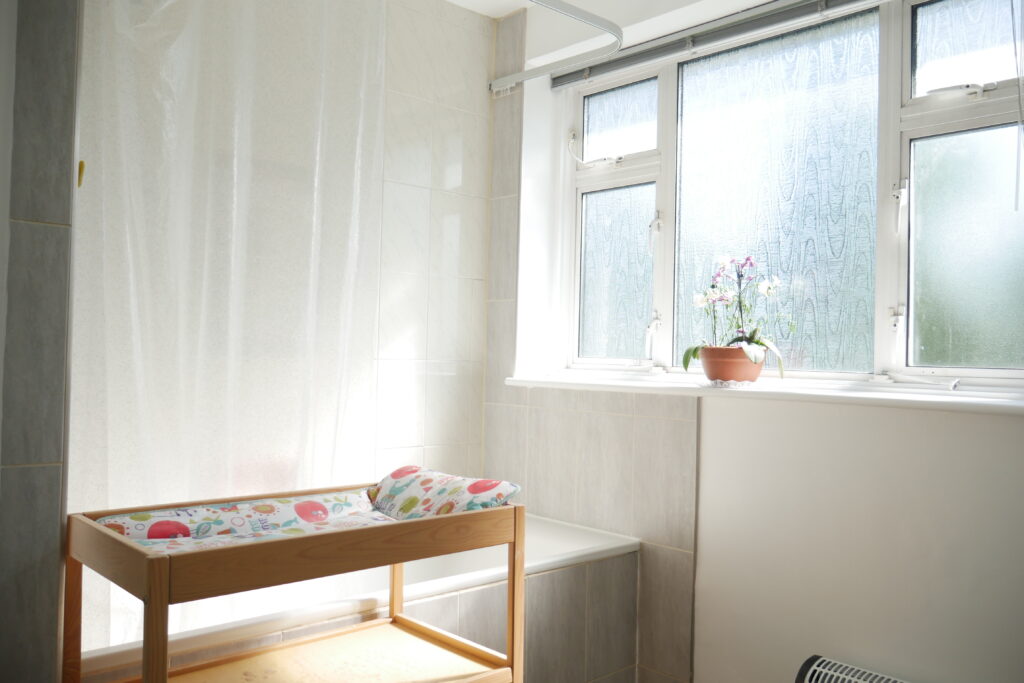 A room with a window and a baby crib
