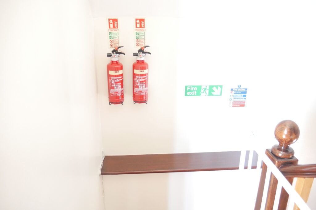 A wall with two fire extinguisher hanging on it.