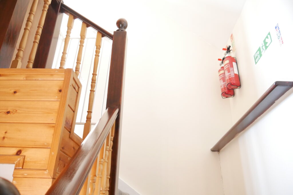 A wooden staircase with a red and white dress hanging on the wall.