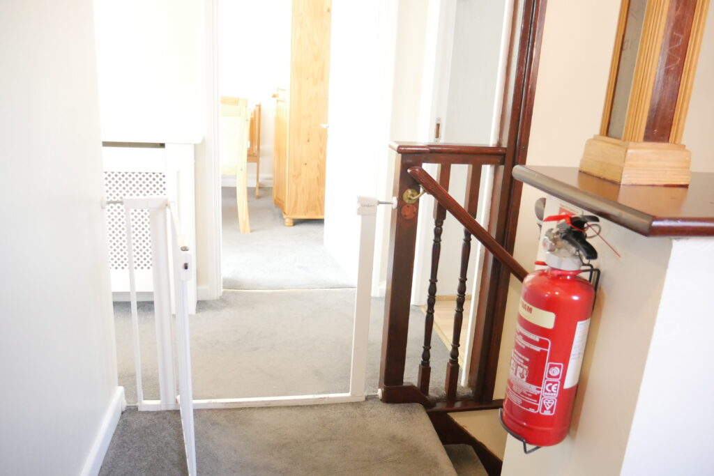A fire extinguisher is on the floor near an open door.