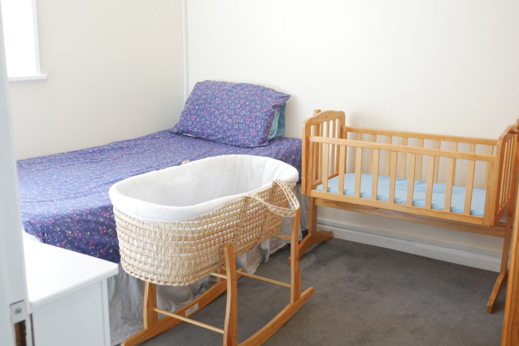 A crib and bed in a room with a blue blanket.