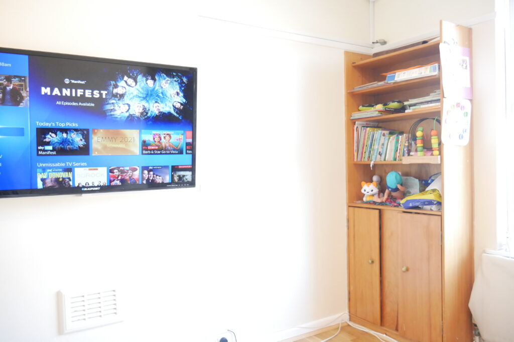 A television is mounted on the wall above a book shelf.
