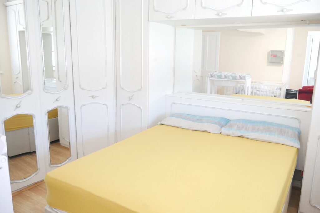 A bedroom with yellow sheets and white walls